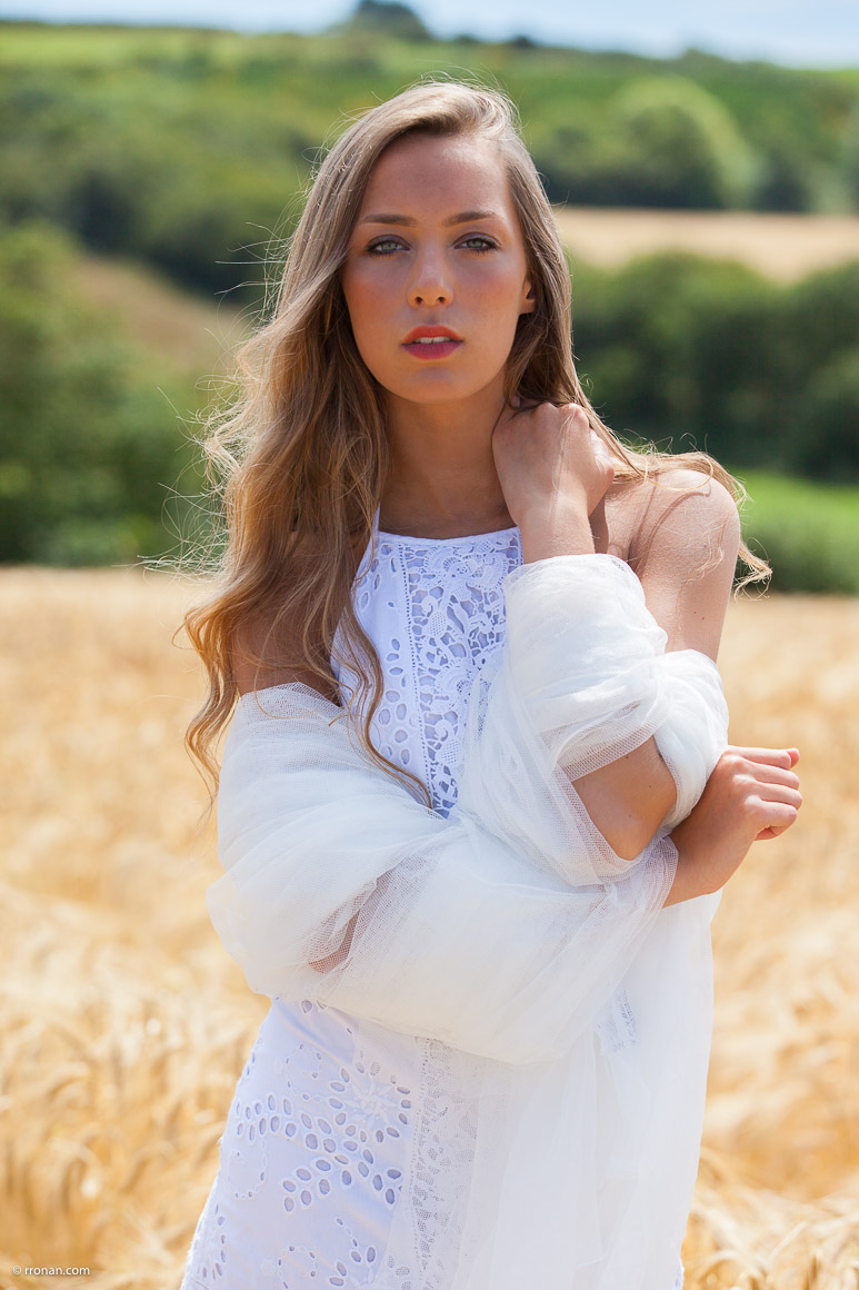 Mathilde en robe blanche et voile dans un champs de blé sur Lanildut